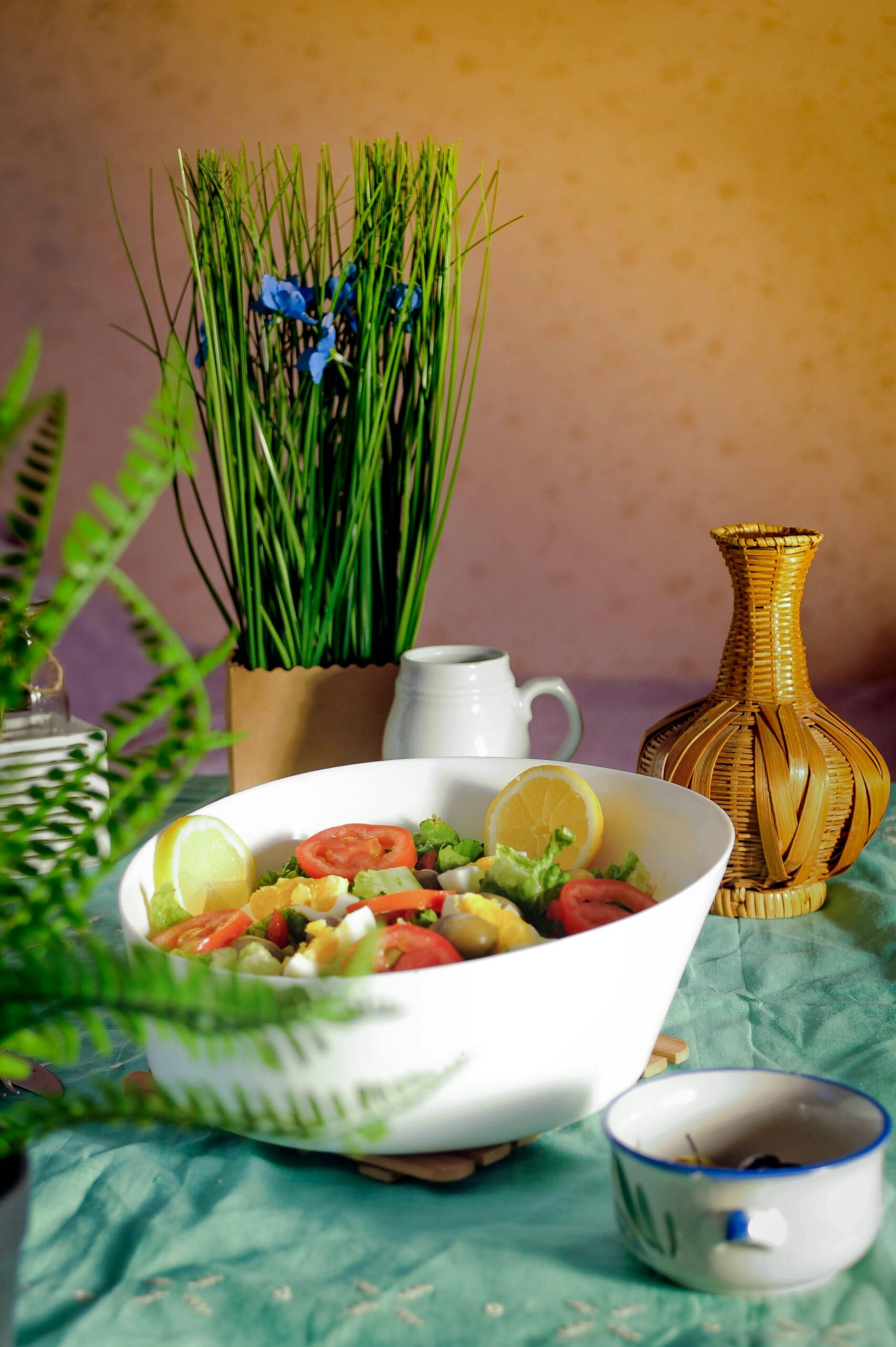 A vibrant fresh salad in a white bowl surrounded by tropical home decor elements.